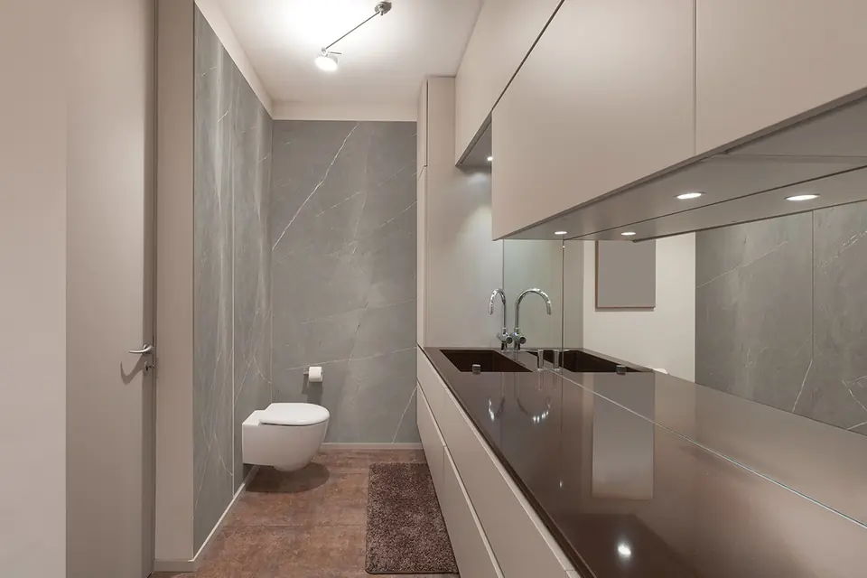 Bagno con parete rivestita in grandi lastre di gres porcellanato grigio